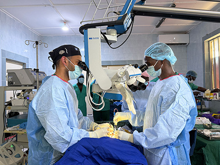 Two doctors perform surgery in The Gambia