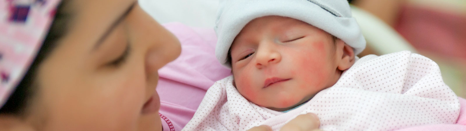 Mother looking down at newborn baby in her arms