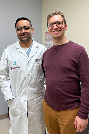 A doctor in his lab coat and a male patient standing and smiling