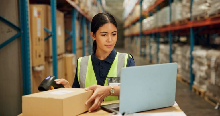 A warehouse worker uses inventory management software – part of a comprehensive logistics service. Professional logistics providers use skilled staff and technology to manage storage and shipments efficiently.