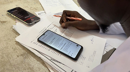 Someone reviews neurology research packets and information on their phone in The Gambia