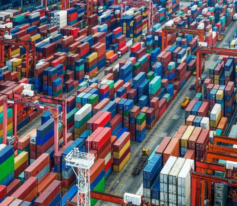 Shipping containers stacked at a busy U.S. port during peak import season, illustrating port congestion and global supply chain logistics.