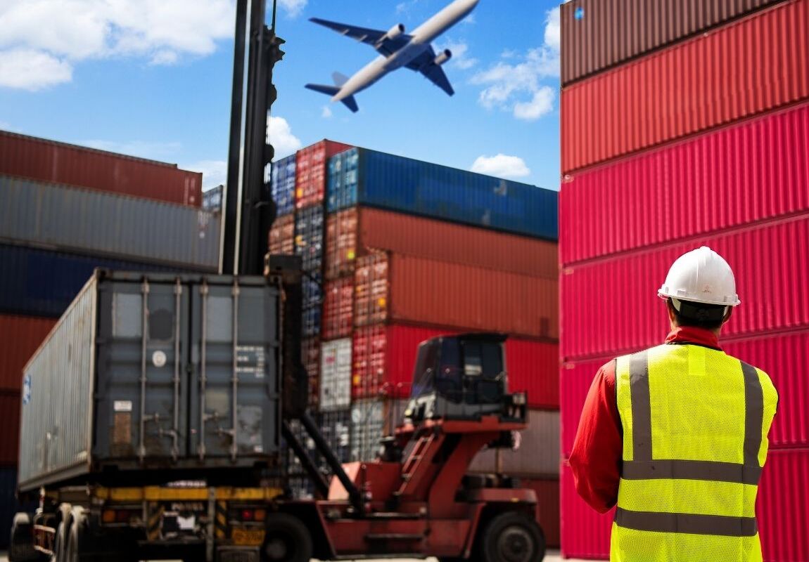 Crane lifting steel coil during rail‑to‑truck transload