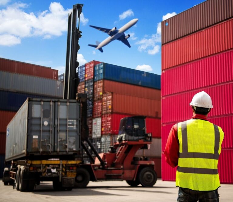 Crane lifting steel coil during rail‑to‑truck transload