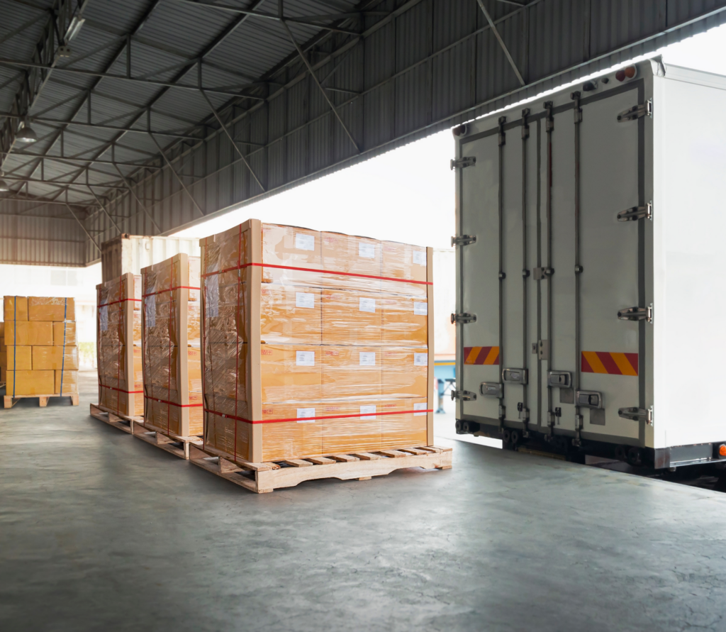 Workers restacking shifted cargo and repairing damaged pallets inside a long beach warehouse facility.